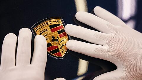 Ein Mitarbeiter befestigt in der "Exterieur Linie" eines Porsche Werks das Wappen an einem Porsche Macan.