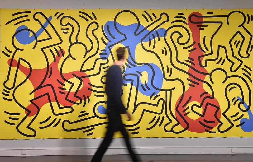 Ein Besucher vor Keith Harings Strichmännchen.