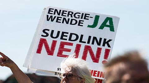 Ein Demonstrant hält ein Schild mit der Aufschrift "Südlink Nein". Foto: Swen Pförtner/dpa/Archivbild