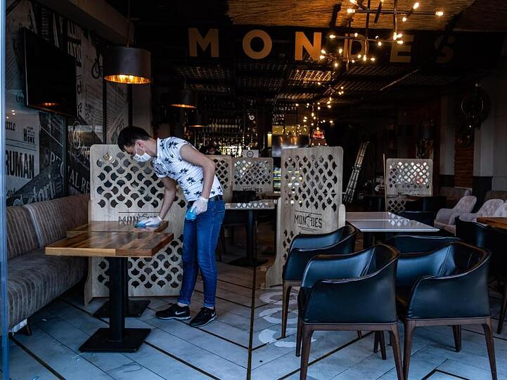 Ein Mitarbeiter reinigt die Tische eines Restaurants in Istanbul vor der Wiedereröffnung.