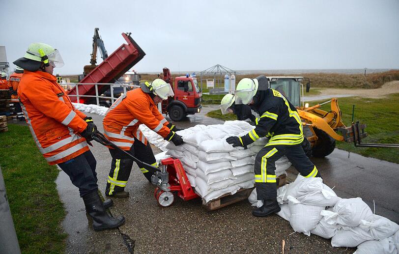 Feuerwehrleute sichern den Deich in Cuxhaven-Sahlenburg (Niedersachsen) mit Sandsäcken