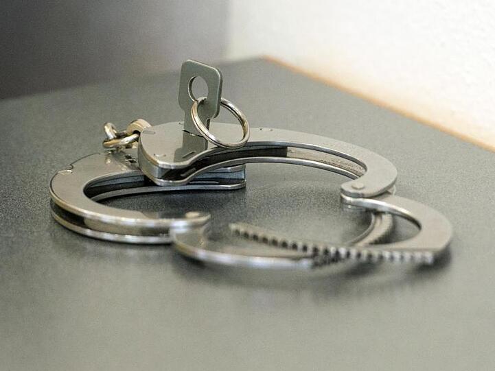 Handschellen liegen auf einem Tisch. Foto: Armin Weigel/dpa/Symbolbild