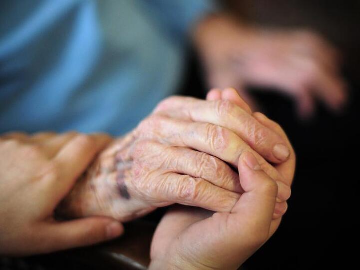 Eine Pflegekraft hält in einem Seniorenheim die Hand einer Bewohnerin. Foto: Daniel Reinhardt/dpa