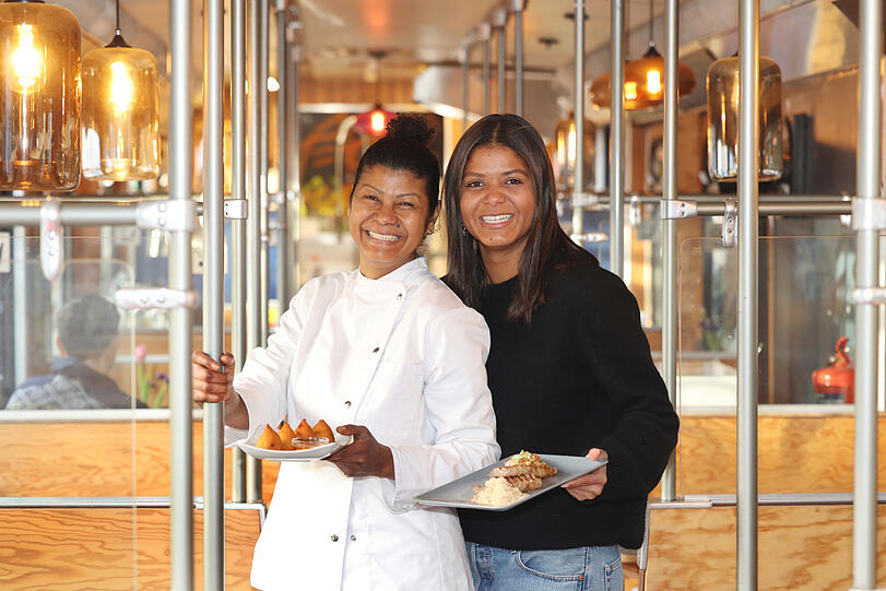 Paula Fehr (l.) und ihre Tochter Fernanda Rodrigues servieren Salgados, frittierte Kartoffelkroketten mit verschiedenen Füllungen und Picanha, Tafelspitz-Steak mit brasilianischer Vinaigrette und Maniokschrot.