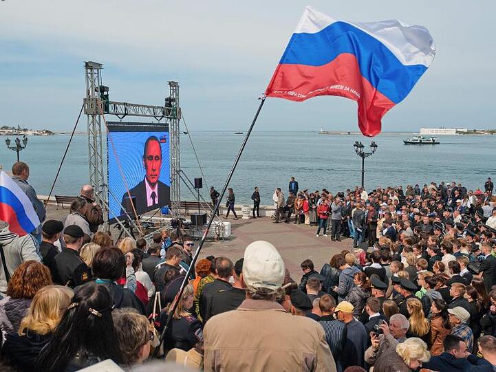 Menschen in Sewastopol bei einer Fernseh-Ansprache von Wladimir Putin: Auf der Krim wird der fünfte Jahrestag der umstrittenen Vereinigung mit Russland gefeiert.