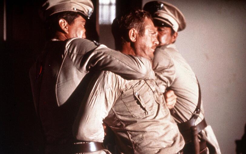 Der aufs&auml;ssige Str&auml;fling Henri Charri&egrave;re alias Papillon (Steve McQueen) wird von W&auml;rtern niedergerungen.