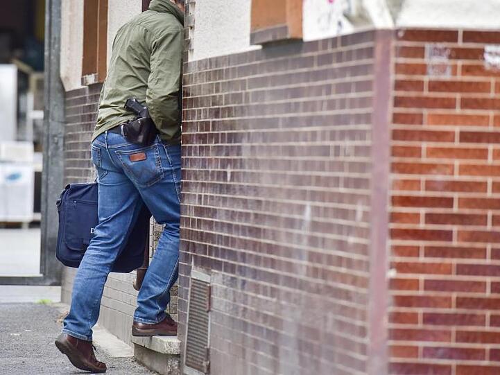 Ein Polizeibeamter betritt ein Haus in Bonn. Laut Staatsanwaltschaft konnten die Beamten mutmaßliche Beweismittel sicherstellen.