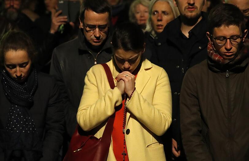 Menschen beten, während die Kathedrale Notre Dame in Paris brennt.