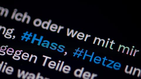 Auf dem Bildschirm eines Smartphones sieht man die Hashtags Hass und Hetze.