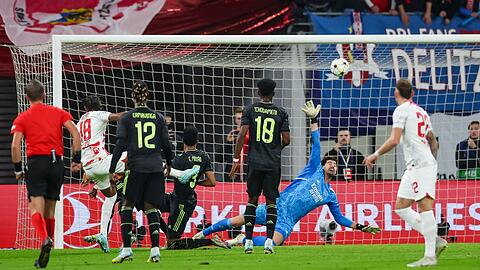 Christopher Nkunku (l/18) trifft für RB Leipzig gegen Reals Torwart Thibaut Courtois zum 2:0.