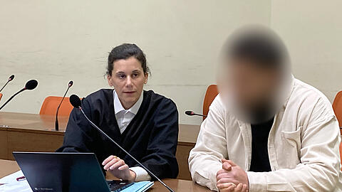 Der 22-jähriger Anklage mit seiner Anwältin Daniela Gabler am Donnerstag im Amtsgericht München. Er soll bei der Flucht vor einer Polizeikontrolle berauscht und ohne Führerschein die Kontrolle über seinen Wagen verloren und in eine Tram-Haltestelle geschleudert sein. Dabei starb ein 18-Jähriger, weitere Menschen wurden verletzt.