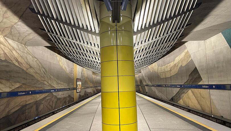 Der U-Bahnhof Gro&szlig;hadern mit gelber S&auml;ule, Wandgem&auml;lde und moderner Lichtabdeckung.
