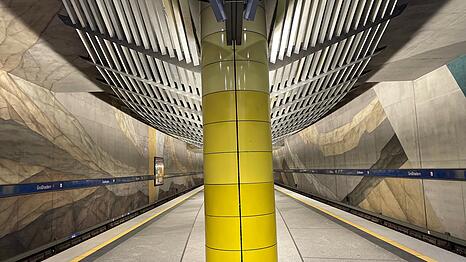Der U-Bahnhof Gro&szlig;hadern mit gelber S&auml;ule, Wandgem&auml;lde und moderner Lichtabdeckung.