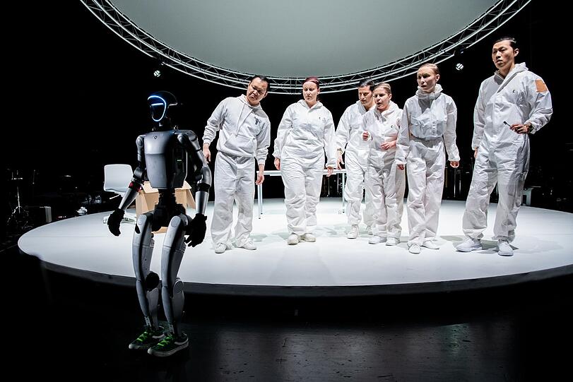 Die Solisten von &bdquo;V01CES//B0D1EZ&ldquo; mit dem Roboter im Akademietheater des Prinzregententheaters.