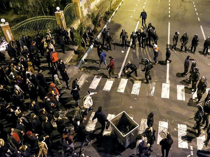 Polizisten stehen Demonstranten vor einer Universität in Teheran gegenüber.