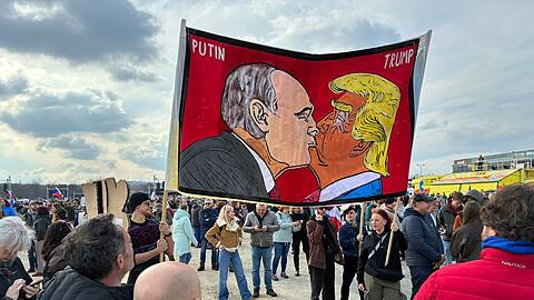 Demonstranten halten bei einer Kundgebung des B&uuml;ndnisses "Eine Million Augenblicke f&uuml;r Demokratie" ein Banner, auf dem sich stilisiert US-Pr&auml;sident Trump und Russlands Pr&auml;sident Putin k&uuml;ssen.