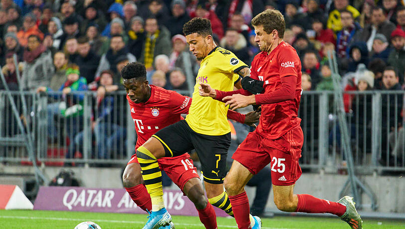 In der Zange: Jadon Sancho (m) behauptet den Ball gegen Thomas Müller (r.) und Alphonso Davies.
