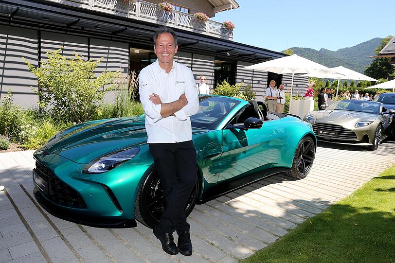 Gastgeber und Zwei-Sterne-Koch Thomas Kellermann lehnt l&auml;ssig am schicken Aston Martin.