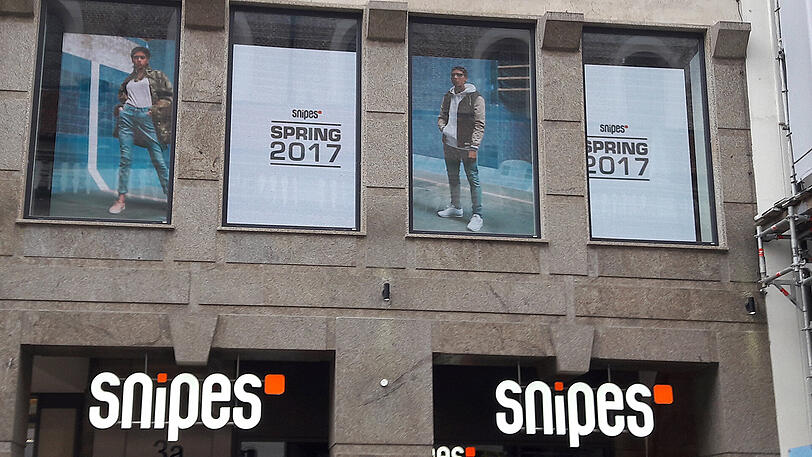 Leuchten verboten: Im ersten Stock über dem Mode- und Sneaker-Geschäft "Snipes" in der Neuhauser Straße flimmern seit Monaten Werbefilmchen in den Schaufenstern. Das stört die Lokalbaukommission, die die Bewegtbilder als "Verunstaltung" im Herzen Münchens ansieht.