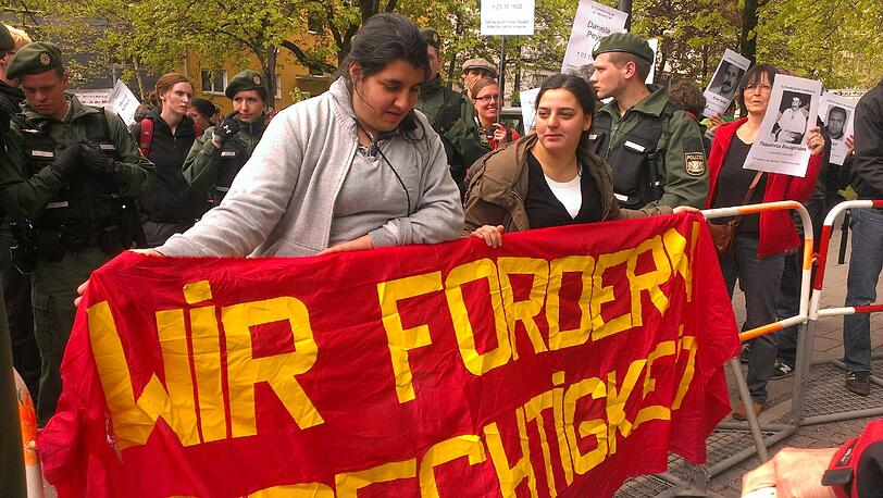 Bilder vom Prozess-Auftakt: Zwei junge, türkischstämmige Frauen fordern auf einem Plakat Gerechtigkeit. Wenig später versuchen die Frauen gewaltsam in die Bannmeile vor dem Gericht einzudringen.