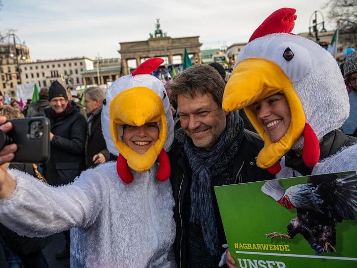Grünen-Chef Robert Habeck (M) posiert mit Demonstranten in Hühnerkostümen für ein Selfie.