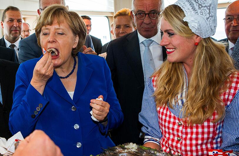 Für die erfahrene Fischesserin Merkel nur ein Haps &ndash; und weg ist das aufgespießte Fischteilchen.