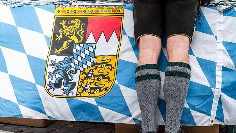 Ein Mann in Tracht steht vor der bayerischen Landesfahne auf dem Gredinger Trachtenmarkt.