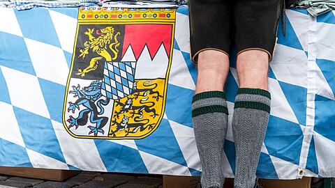 Ein Mann in Tracht steht vor der bayerischen Landesfahne auf dem Gredinger Trachtenmarkt.