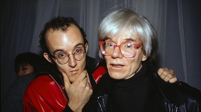 Erst hat sich Keith Haring (links) nicht getraut, den großen Andy Warhol anzusprechen. Dann sind die beiden aber schnell Freunde geworden. Und in diesem Fall wurden sie gleich noch im New Yorker Palladium Club von einer fabelhaften Szenefotokünstlerin abgelichtet: Nan Goldin.