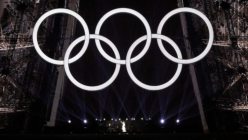 Céline Dion auf dem Eiffelturm unter den olympischen Ringen.