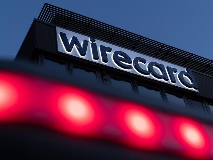 Rote Lichter leuchten vor dem Schriftzug von Wirecard an der Firmenzentrale. Foto: Peter Kneffel/dpa/Archivbild