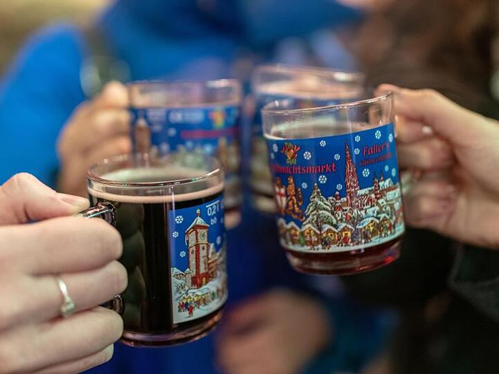 Vier Frauen stoßen auf dem Weihnachtsmarkt mit Glühwein an. Das Deutsche Weininstitut in Mainz stellt einen Trend zu höherwertigen Glühweinen fest.