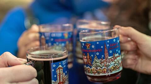 Vier Frauen stoßen auf dem Weihnachtsmarkt mit Glühwein an. Das Deutsche Weininstitut in Mainz stellt einen Trend zu höherwertigen Glühweinen fest.
