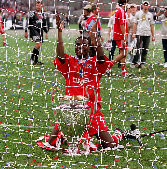 Publikumsliebling Kuffour lässt sich mit Pokal von den Bayern-Fans feiern.