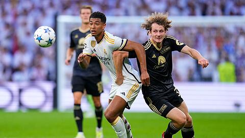 Real Madrids Jude Bellingham (l) und Unions Alex Kral im Zweikampf.