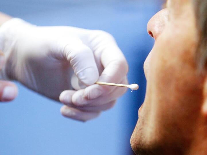 Die Polizei führt bei einem Mann einen DNA-Speicheltest durch.