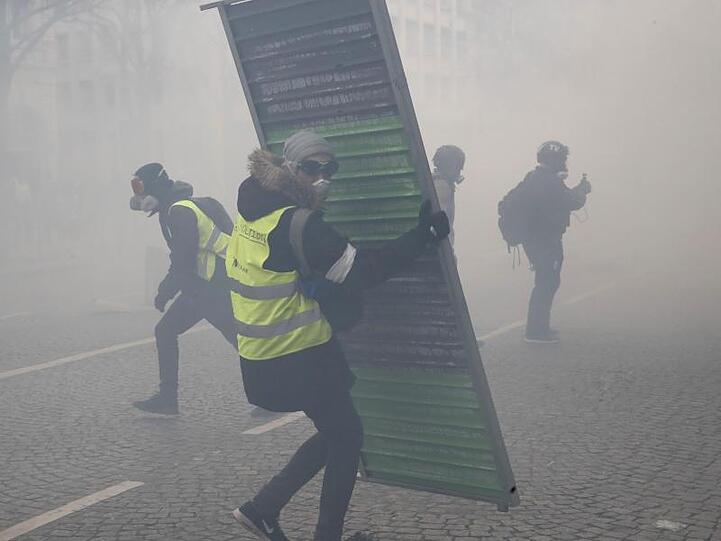 Im Tränengasnebel errichten Demonstranten Barrikaden auf den Champs-Elysees.