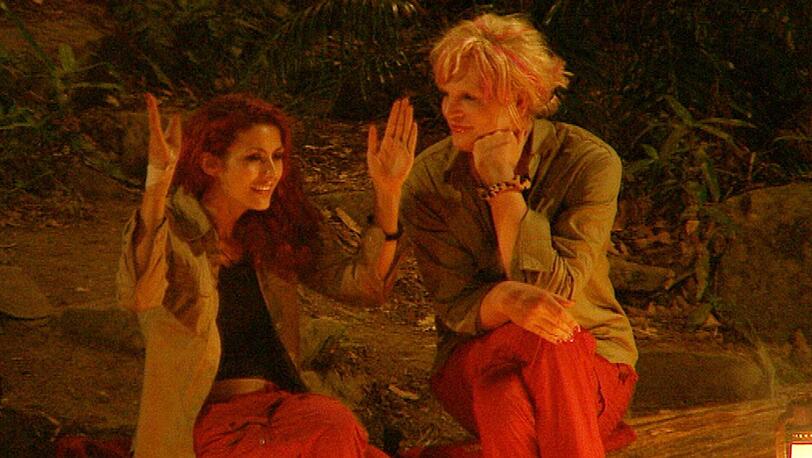 Fiona Erdmann und Olivia Jones sitzen am Lagerfeuer und lästern.