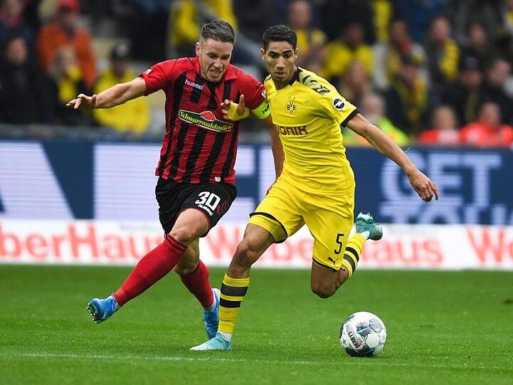 Freiburgs Christian Günter (l) und Dortmunds Achraf Hakimi (r) im Laufduell um den Ball.