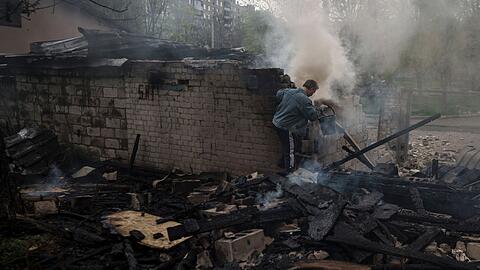 Ein Mann versucht nach einem russischen Bombardement eines Wohnviertels in Charkiw, ein Feuer zu löschen.