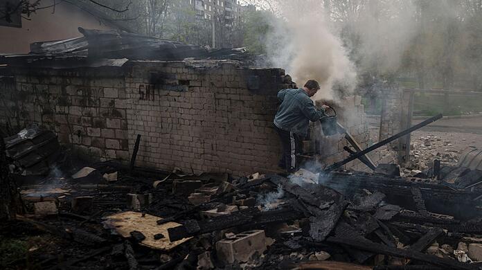 Ein Mann versucht nach einem russischen Bombardement eines Wohnviertels in Charkiw, ein Feuer zu löschen.