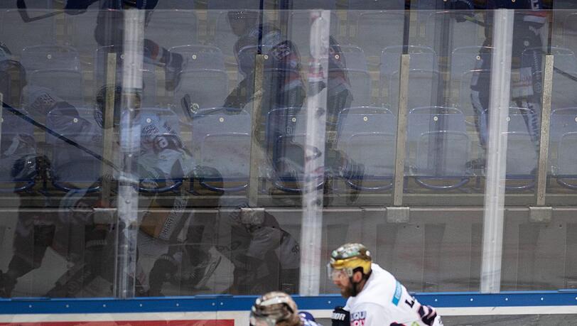 Eishockeyspieler spiegeln sich vor leeren Rängen in der Bande.