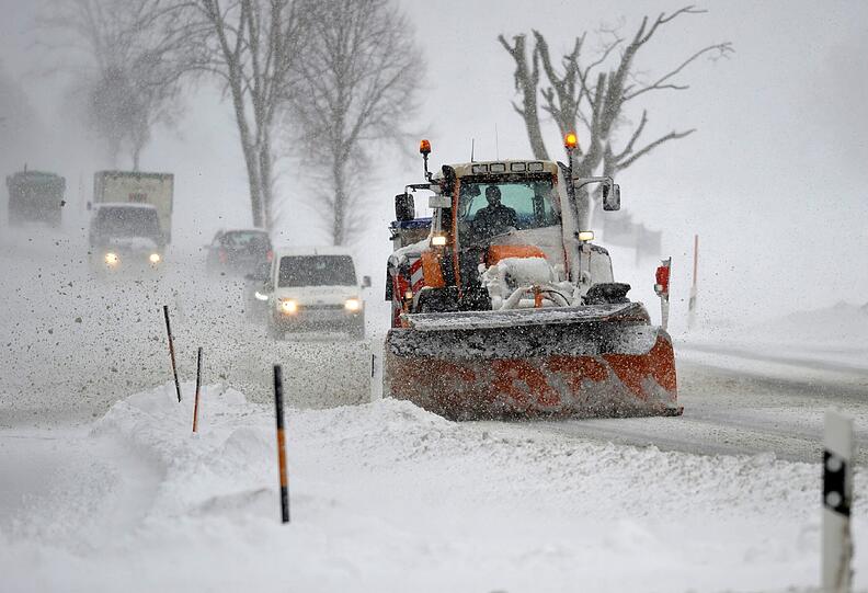 Ein Schneepflug räumt die Straße.