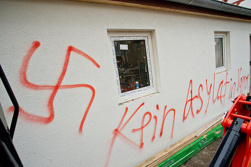 Der Schriftzug «Kein Asylat (Asylant) in Vorra» und Hakenkreuze sind am 12.12.2014 in Vorra (Bayern) an einer Hauswand zu lesen. In der Nacht hatten im Ortskern des Dorfes im Kreis Nürnberger Land ein ehemaliger Gasthof, ein nahe gelegenes Wohnhaus sowie eine Scheune gebrannt. In die Gebäude sollten in der kommenden Woche Asylbewerber einziehen.