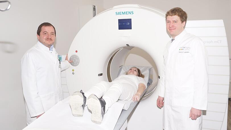 Dr. med. Christopher Übleis (links) und Dr. med. Thorsten Johnson zeigen den neuen PET/CT am Standort Großhadern.