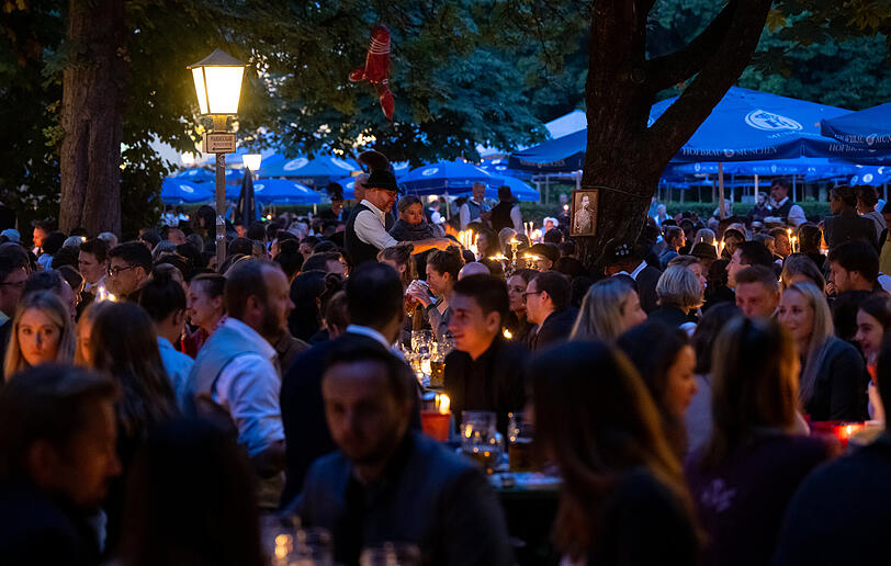 Zahlreiche Besucher des traditionellen Kocherlball sitzen am Chinesischen Turm im Englischen Garten an Biertischen.