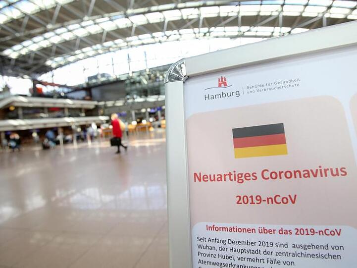 Auf einem Aufsteller der Gesundheitsbörde und des Robert Koch-Instituts wird im mäßig gefüllten Hamburger Flughafen auf Verhaltensweisen in Bezug auf das Coronavirus hingewiesen.