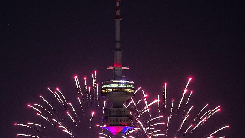 Der Himmel hinter dem Olympiaturm wird durch Feuerwerksraketen hell in einem Rosa-Ton erleuchtet. Der Himmel hinter dem Olympiaturm wird durch Feuerwerksraketen hell in einem Rosa-Ton erleuchtet.