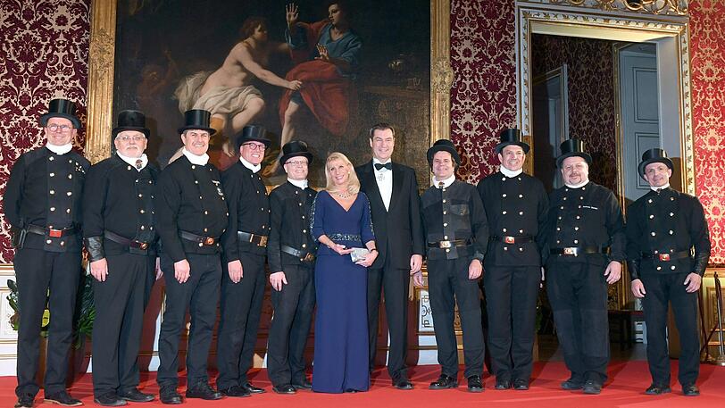 Markus Söder (CSU), Ministerpräsident (r) und seine Frau Karin Baumüller-Söder (m) stehen zusammen mit einer Gruppe von Kaminkehrern beim Defilee des Neujahrsempfang in der Münchner Residenz.