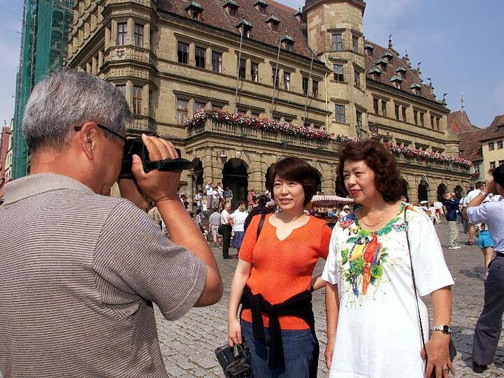 Japanische Touristen vor dem Renaissance-Rathaus in Rothenburg ob der Tauber.